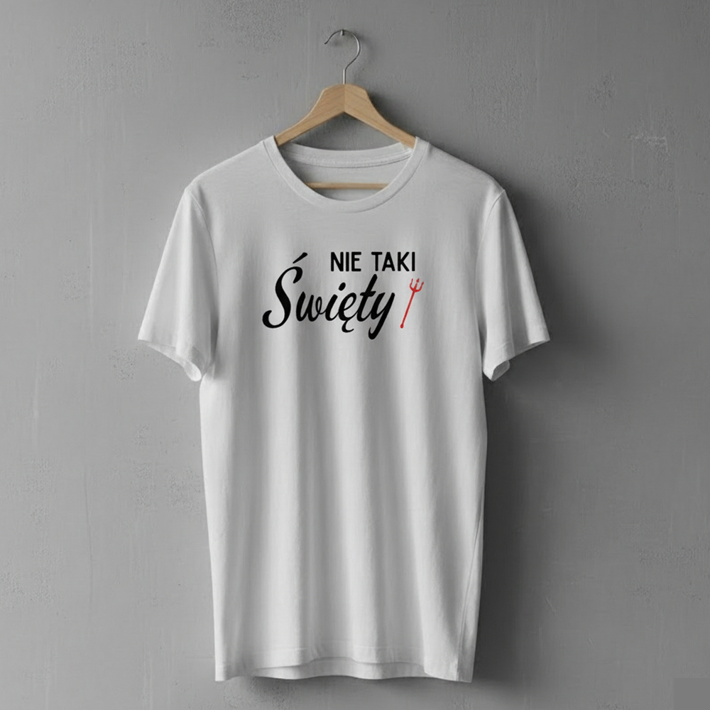 Biała koszulka wisząca na drewnianym wieszaku, ozdobiona napisem ‘Nie taki Święty’ z małą czerwoną trójzębną widłami obok