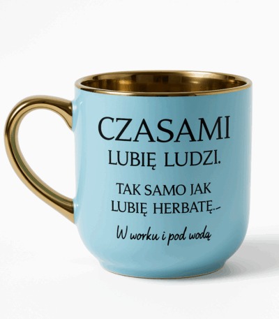 Błękitny kubek ze złotym uchem i złotym wnętrzem, ozdobiony humorystycznym napisem: ‘Czasami lubię ludzi. Tak samo jak lubię herbatę — w worku i pod wodą’