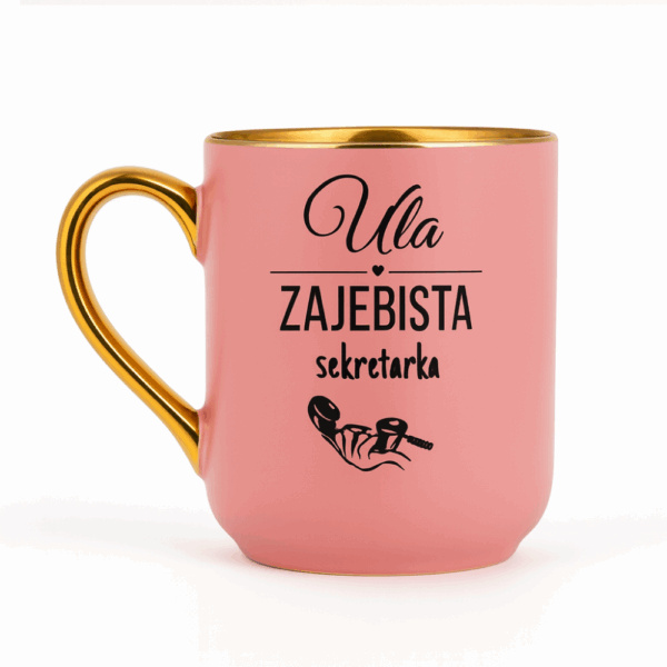 Różowy kubek ze złotym uchem i rantem, ozdobiony napisem ‘Ula – zajebista sekretarka’ oraz grafiką dłoni trzymającej słuchawkę telefonu