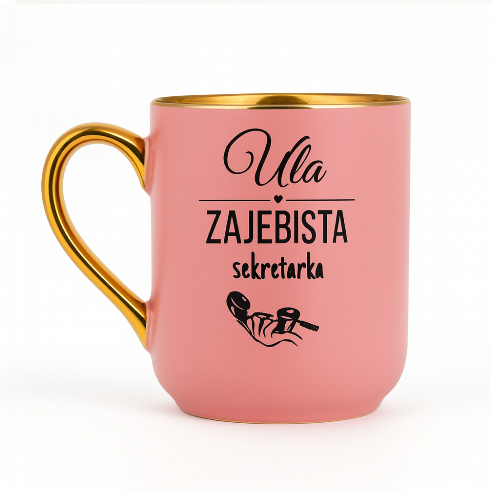 Różowy kubek ze złotym uchem i rantem, ozdobiony napisem ‘Ula – zajebista sekretarka’ oraz grafiką dłoni trzymającej słuchawkę telefonu